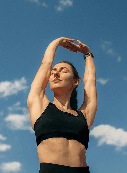 Person stretching outdoors under a blue sky