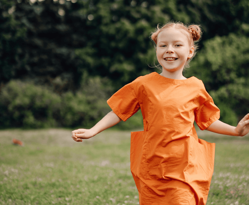 Child running outdoors in an orange outfit